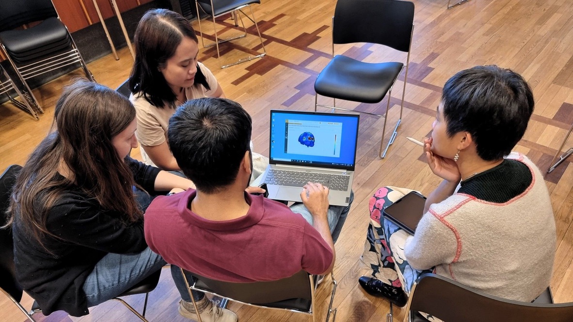 A group of researchers at a workshop at the University of Oslo examines an image of a brain showing EEG data
