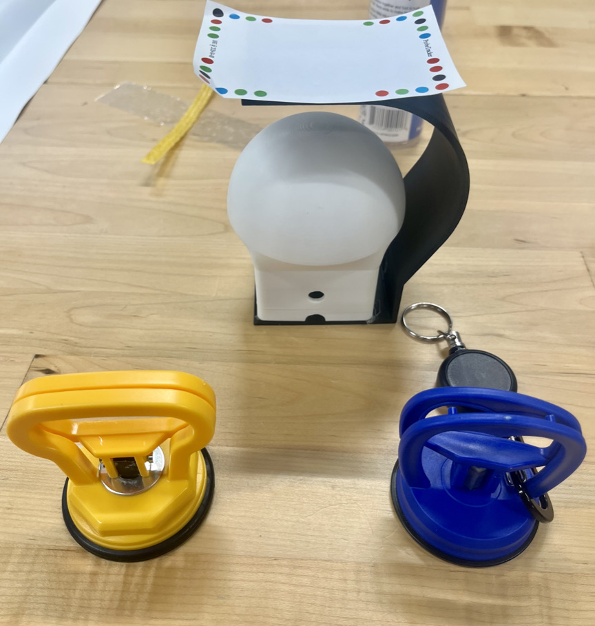 Example TeleTangibles modules: two clamps with extendable lanyards attached to them that attach to the desk and a grippable slider containing a vibration motor.