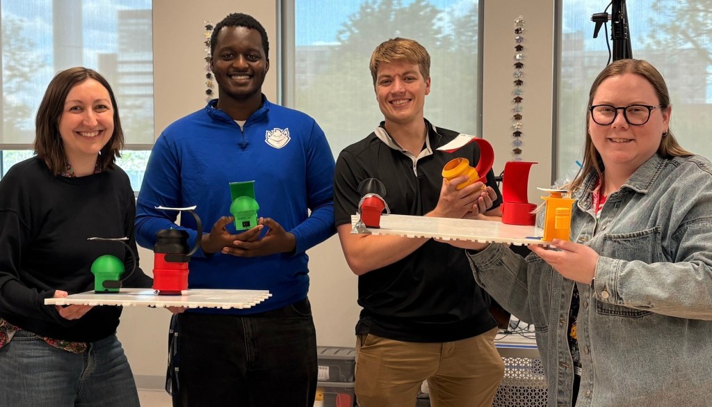 Holding up assorted colorful TeleTangibles haptic prototypes at the CHROME lab at Saint Louis University.